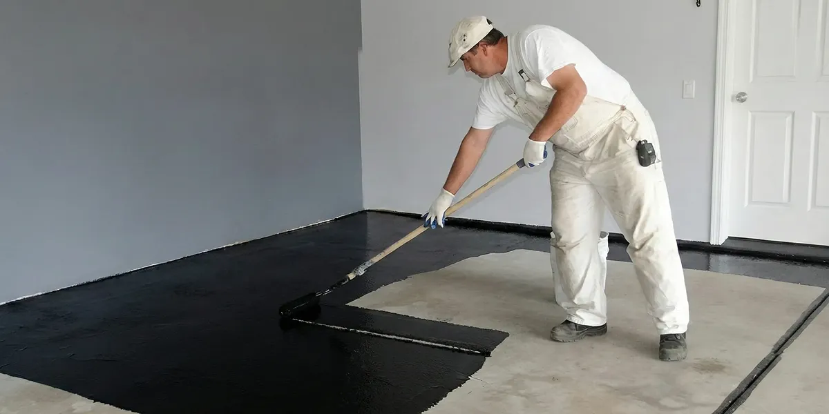 basement waterproofing professional applying waterproof coating to protect a basement floor in Worcester, MA